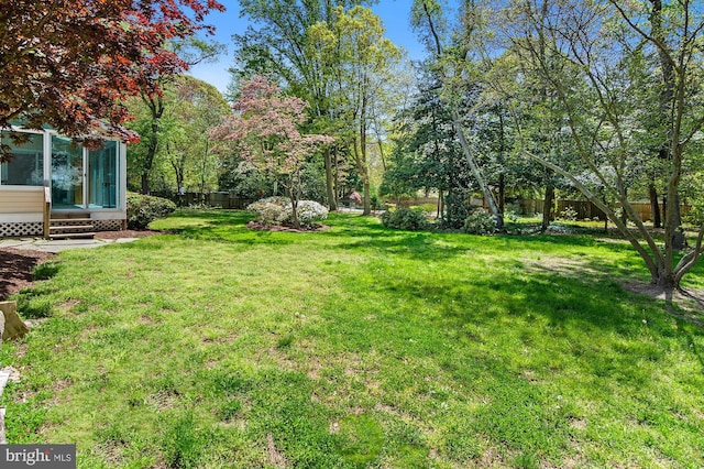 view of yard featuring fence and a sunroom