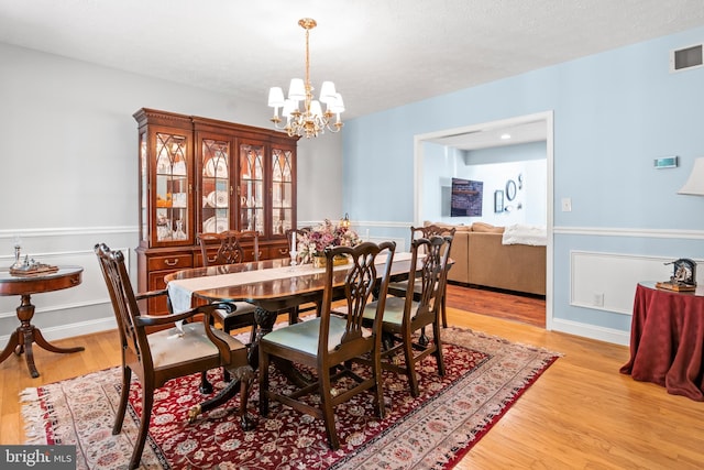 dining area featuring visible vents, light wood-type flooring, and an inviting chandelier