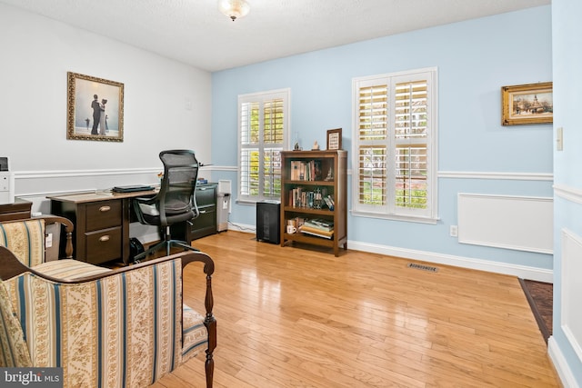office space with a textured ceiling, baseboards, visible vents, and wood finished floors
