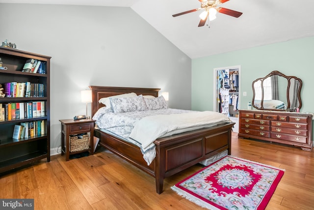bedroom with a closet, a walk in closet, vaulted ceiling, and wood finished floors