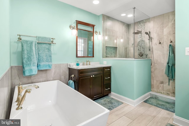 full bath featuring vanity, walk in shower, wood finish floors, recessed lighting, and a soaking tub