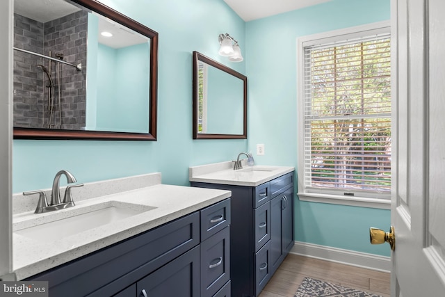 full bathroom featuring baseboards, two vanities, a sink, and wood finished floors