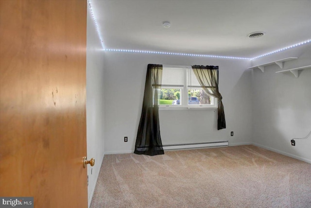 empty room featuring baseboard heating, visible vents, carpet, and baseboards