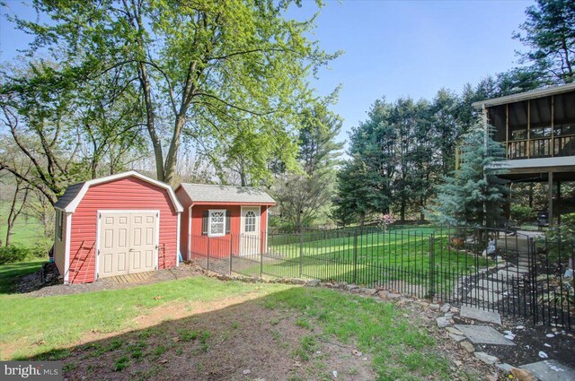 view of yard with a detached garage, a shed, an outbuilding, fence private yard, and a sunroom