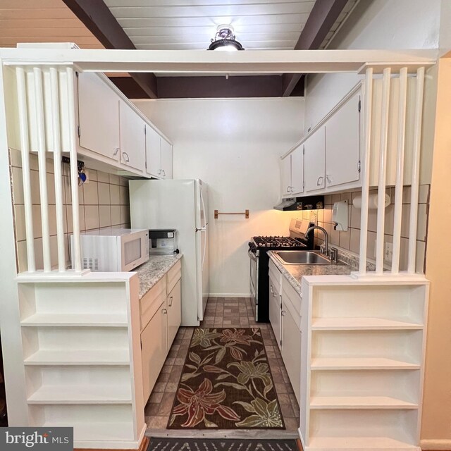 kitchen featuring white appliances, open shelves, backsplash, a sink, and white cabinetry