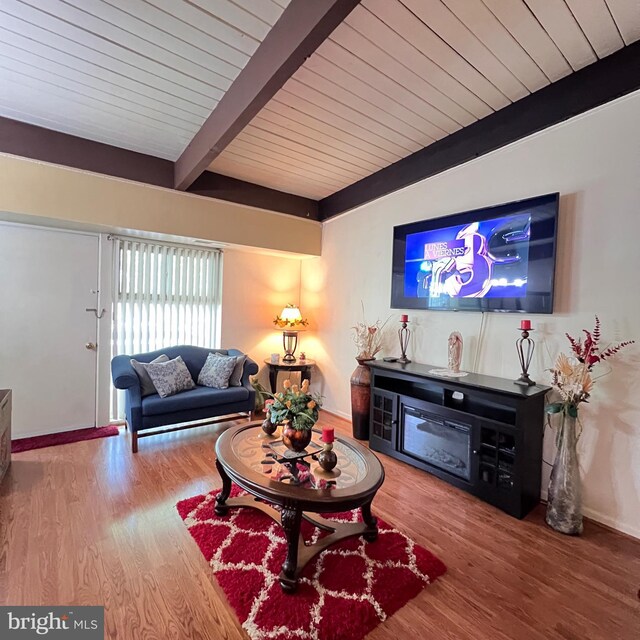 living room featuring wooden ceiling, beam ceiling, wood finished floors, and baseboards