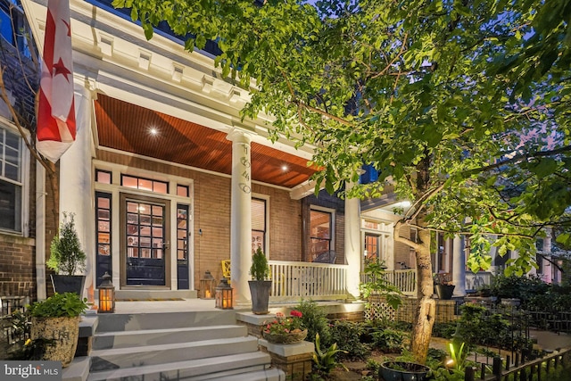 property entrance featuring covered porch and brick siding