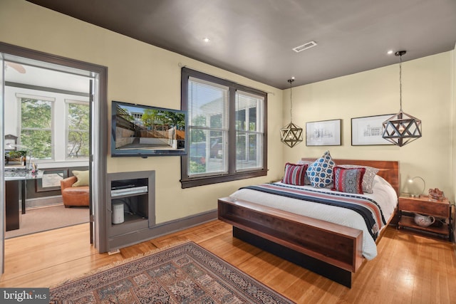 bedroom with baseboards, wood finished floors, and visible vents