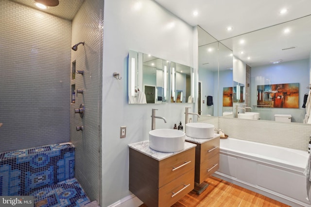 full bathroom with vanity, wood finished floors, and tiled shower