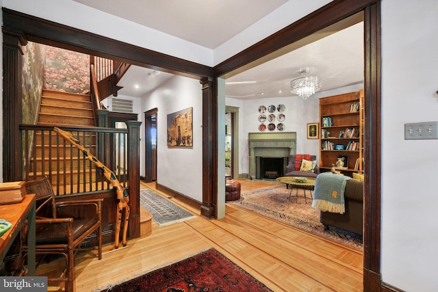 interior space with an inviting chandelier, stairs, wood finished floors, a fireplace, and baseboards
