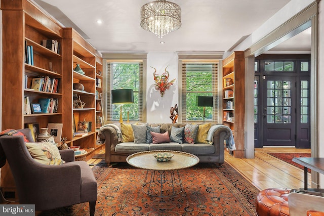 sitting room with a notable chandelier, ornamental molding, and wood finished floors