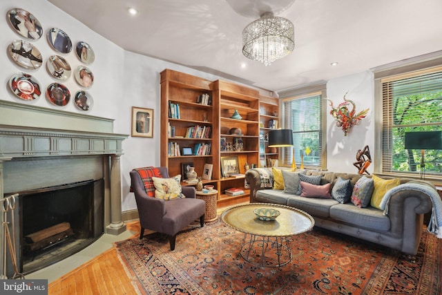 living room featuring wood-type flooring, a fireplace with flush hearth, recessed lighting, and an inviting chandelier