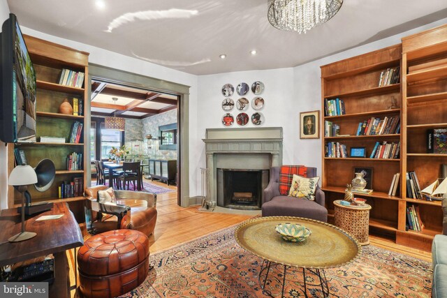 living area featuring recessed lighting, baseboards, a fireplace with flush hearth, wood finished floors, and coffered ceiling