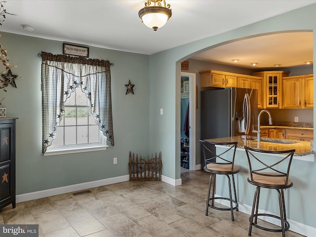 2004 State Road 259 N, Wardensville, WV 26851 - kitchen featuring a kitchen breakfast bar, arched walkways, a sink, stone countertops, and glass insert cabinets