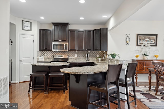 155 Tollerton Trl, Falling Waters, WV 25419 - kitchen featuring stainless steel appliances, a breakfast bar area, a sink, light stone countertops, and recessed lighting