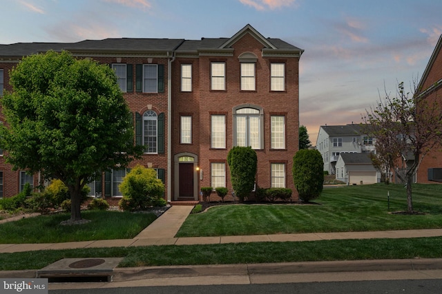townhome / multi-family property with brick siding, a front yard, and central AC