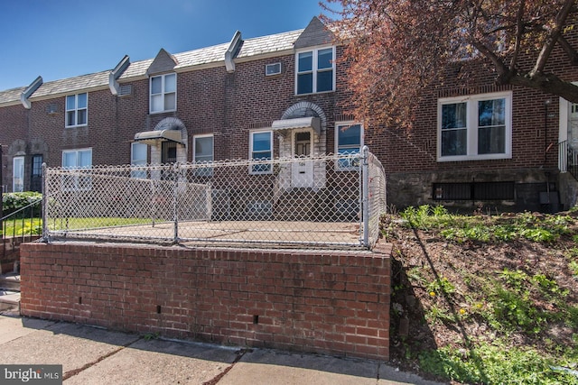 view of property featuring brick siding, a high end roof, and fence private yard