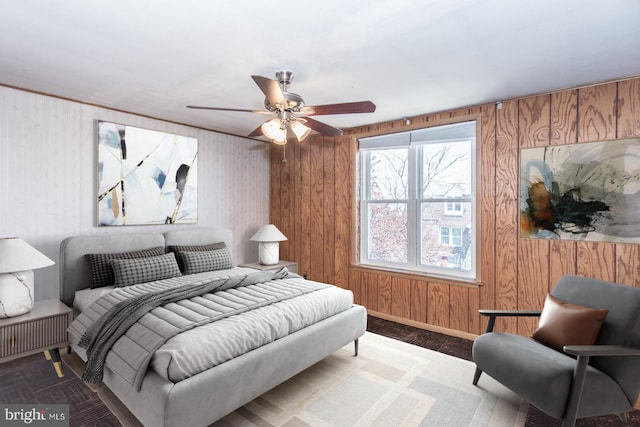 bedroom featuring baseboards, a ceiling fan, and wood walls
