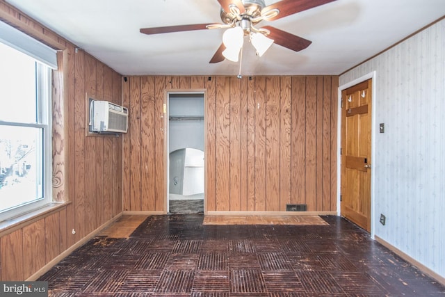 unfurnished room with a ceiling fan, arched walkways, a wall mounted air conditioner, baseboards, and wooden walls