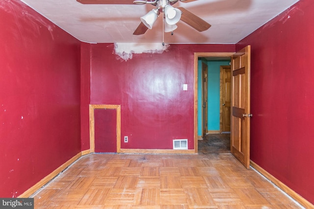 empty room featuring visible vents, a ceiling fan, and baseboards
