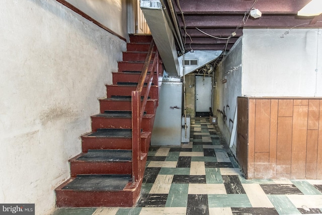 stairway with heating unit, tile patterned floors, and visible vents
