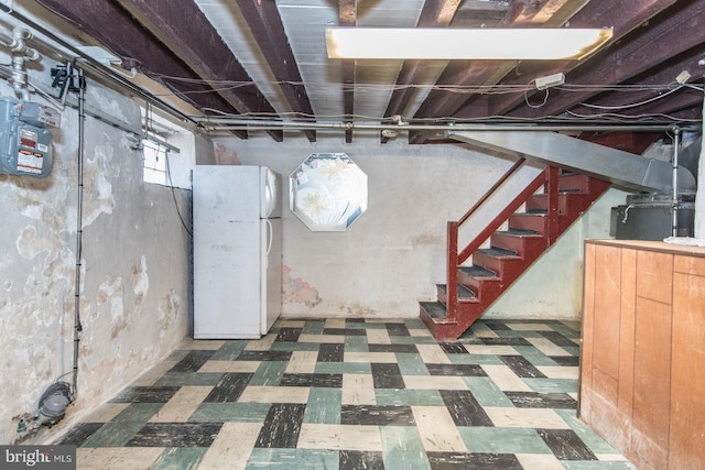 below grade area with freestanding refrigerator, stairs, and tile patterned floors