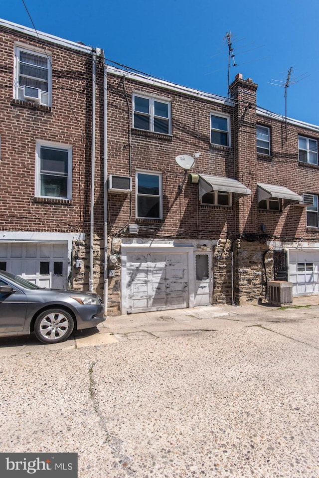 townhome / multi-family property with brick siding, central AC, driveway, and an attached garage
