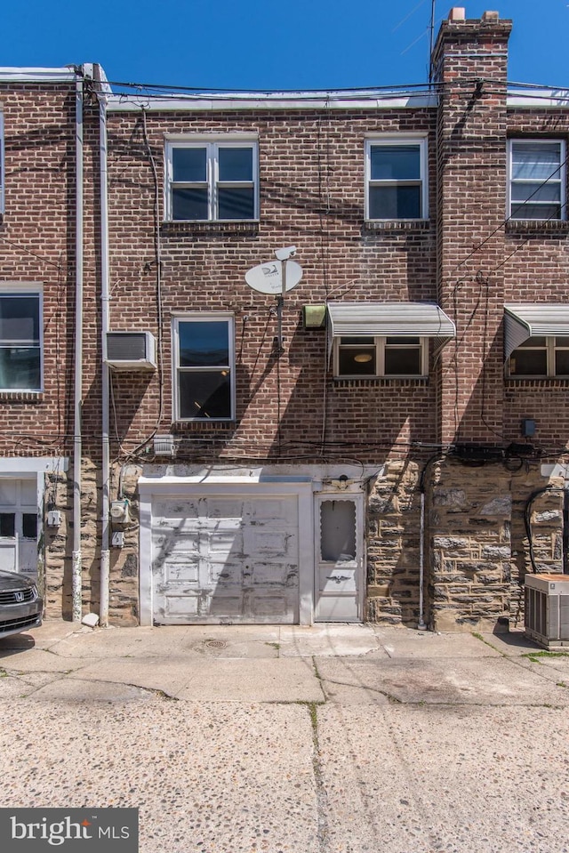 multi unit property with a garage, central AC unit, driveway, and brick siding