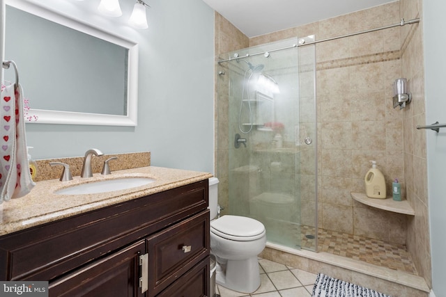 bathroom featuring toilet, vanity, a shower stall, and tile patterned floors