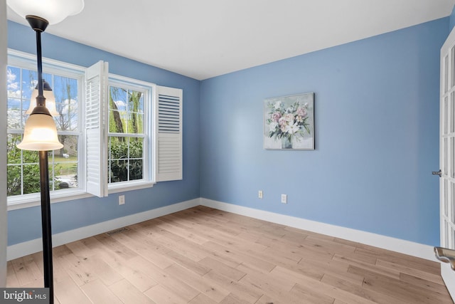 spare room with visible vents, plenty of natural light, light wood finished floors, and baseboards