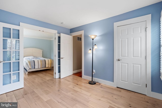 bedroom with visible vents, light wood-style flooring, and baseboards