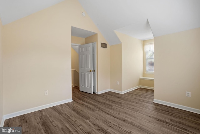 additional living space featuring baseboards, visible vents, wood finished floors, and vaulted ceiling