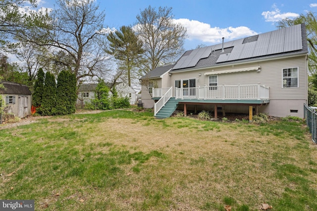 back of house with an outdoor structure, a deck, crawl space, solar panels, and a yard