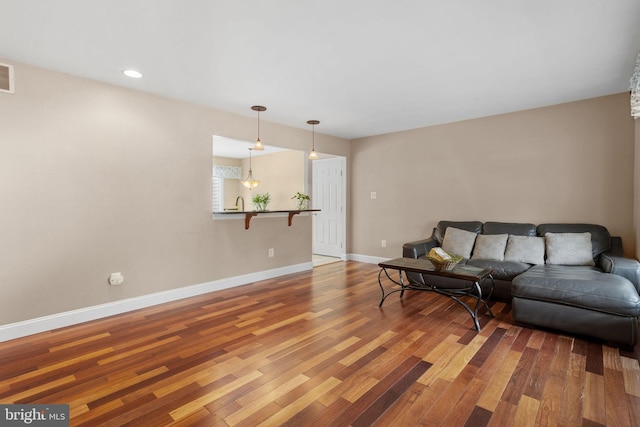 living area with baseboards, visible vents, wood finished floors, and recessed lighting