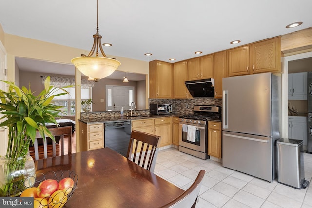 kitchen with light tile patterned floors, tasteful backsplash, a sink, appliances with stainless steel finishes, and dark countertops