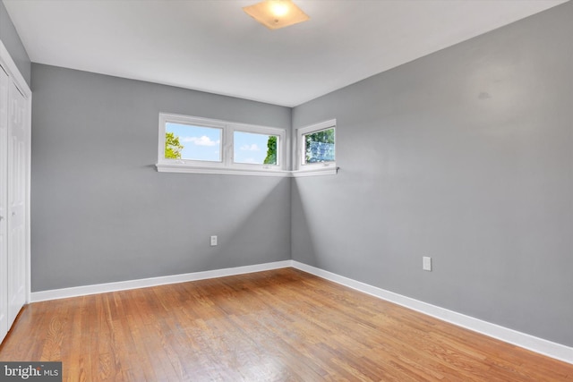 unfurnished bedroom featuring a closet, light wood-style flooring, and baseboards