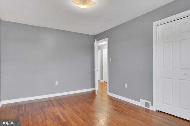 empty room with baseboards, visible vents, and wood finished floors