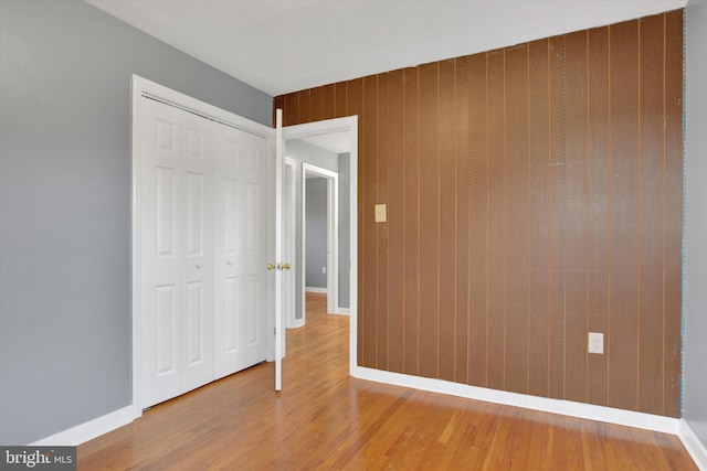 unfurnished bedroom featuring wood finished floors, a closet, and baseboards