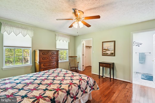 bedroom featuring a textured ceiling, a spacious closet, wood-type flooring, and multiple windows