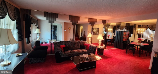 living room featuring a textured ceiling, an inviting chandelier, plenty of natural light, and carpet