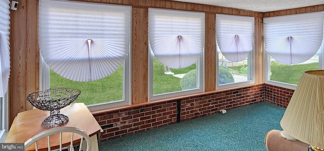 sunroom with carpet flooring, a textured ceiling, and brick wall