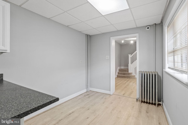 412 Market St, Trenton, NJ 08611 - interior space with light wood-style flooring, stairway, baseboards, a drop ceiling, and radiator heating unit