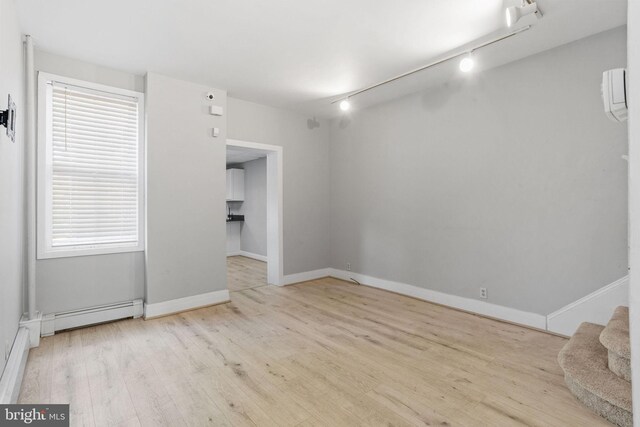412 Market St, Trenton, NJ 08611 - spare room with stairway, a baseboard heating unit, baseboards, rail lighting, and wood finished floors