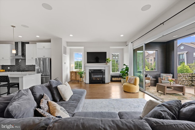 living area featuring light wood-style floors, recessed lighting, and a fireplace with flush hearth