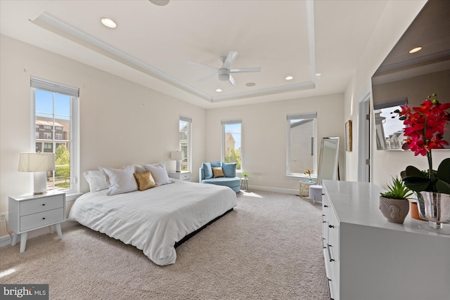 bedroom with a tray ceiling, multiple windows, baseboards, recessed lighting, and light carpet
