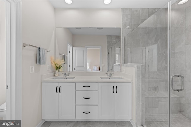 full bath featuring a stall shower, baseboards, double vanity, toilet, and tile patterned flooring