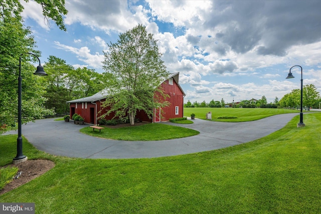 view of community with a barn, a yard, an outbuilding, driveway, and a garage