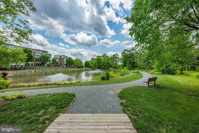view of property's community with a water view and a lawn