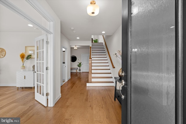 foyer with light wood finished floors, stairway, baseboards, and recessed lighting