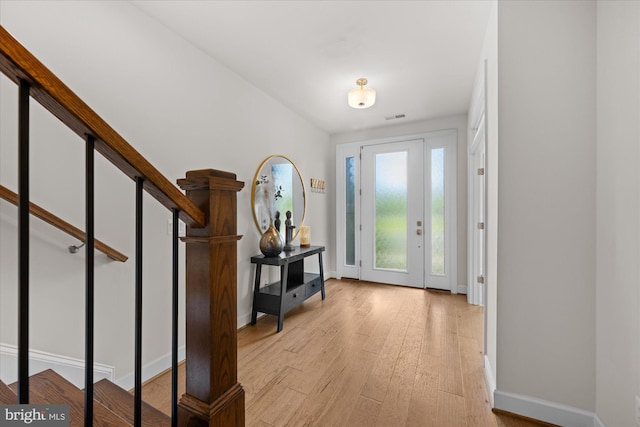 foyer featuring baseboards, light wood-style flooring, and stairway